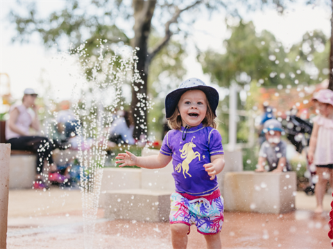 Happy toddler playing in a water park