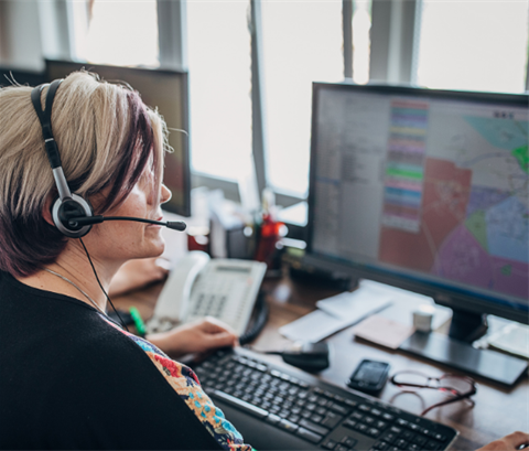 Person with a headset on seated at a computer.