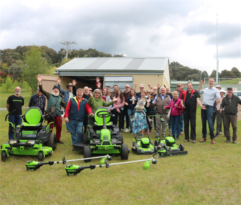 Group of people celebrating with new gardening equipment in foreground
