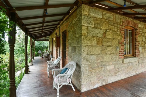 Verandah of a sandstone cottage with which wicker chairs